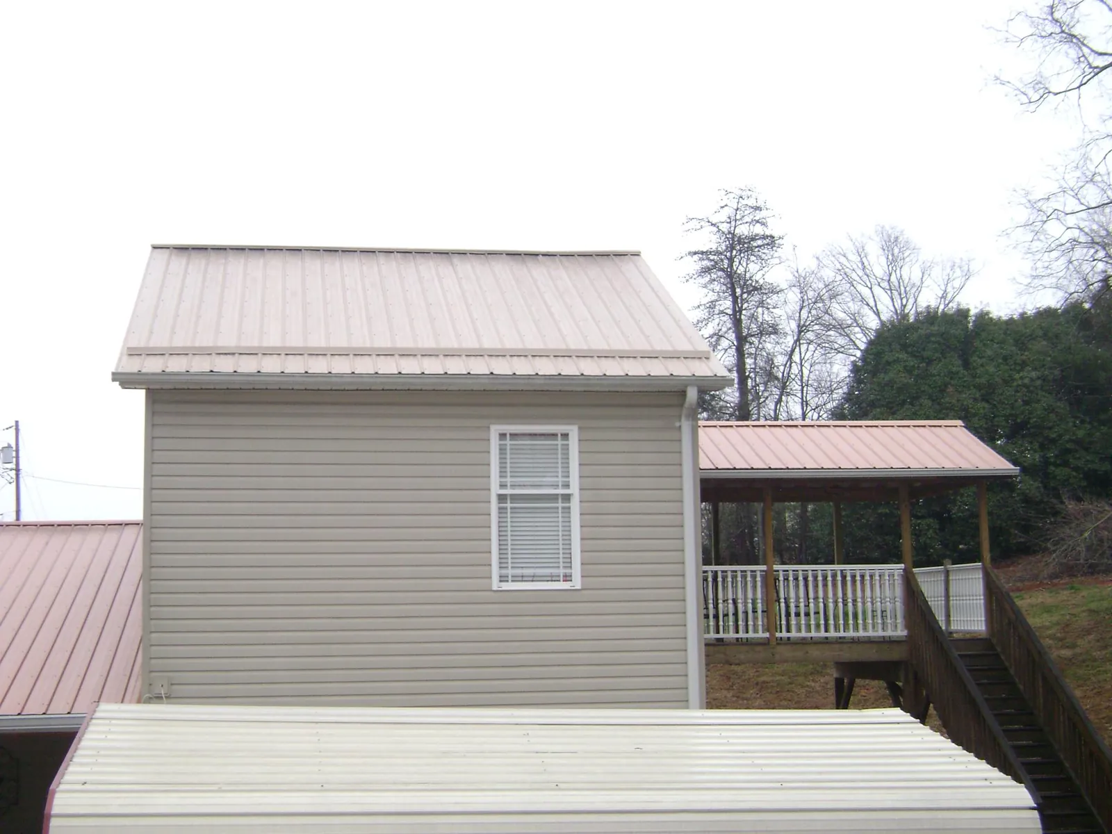 Tan metal roofs on a two story addition and attached porch, from a Roof Replacement job in Parma